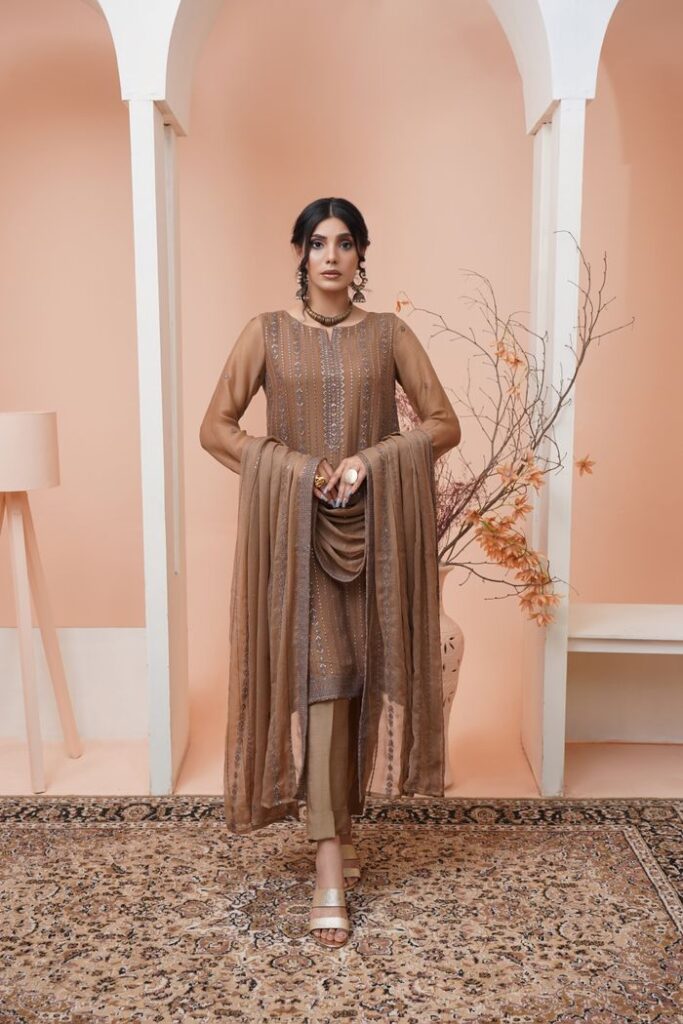 A woman poses in elegant, traditional attire in a Lahore studio setting.